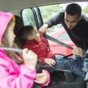 A father makes sure his children are buckled in.