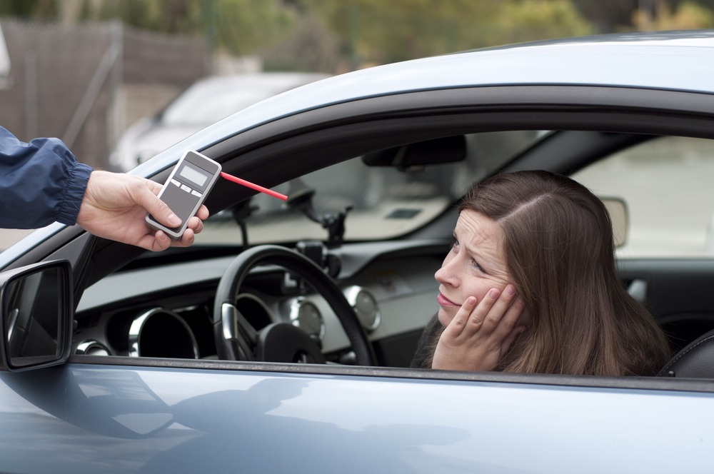 female motorist looks despondently at failed breathalyzer test