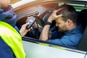 motorist holds head as officer shows him breathalyzer results