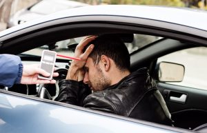 motorist holds head in guilt next to failed breathalyzer test.