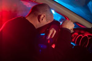 police lights flash on upset motorist holding beer bottle