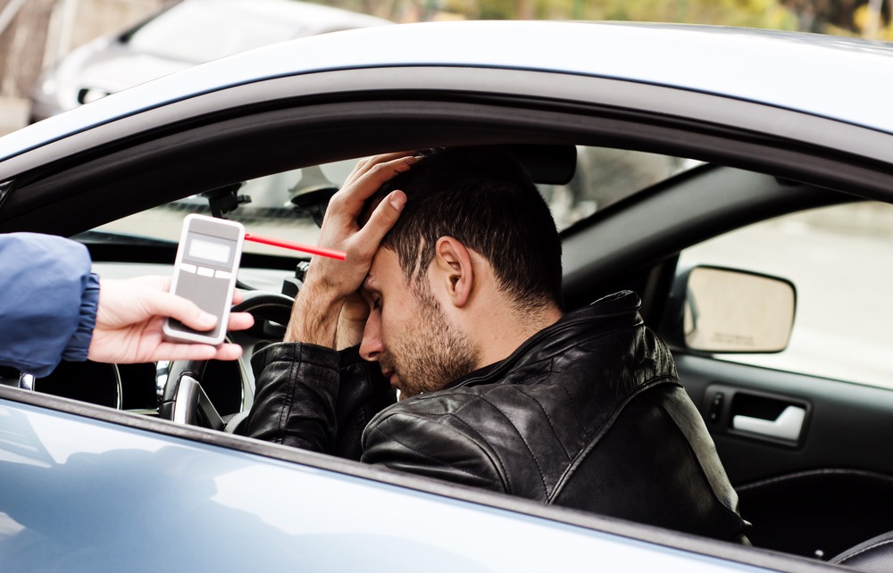 police officer administering breathalyzer test to driver