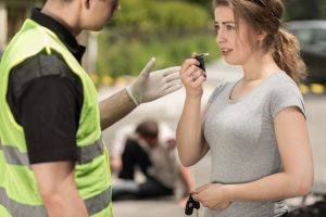 Police officer instructing woman to perform breathalyzer test