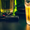 A pair of car keys next to a glass of liquor at a bar.