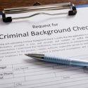 A pen rests on top of a blank criminal background check form.