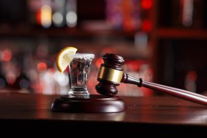 A shot of liquor next to a wooden gavel at a bar.