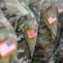 Military servicemen standing with American patches on their shoulders.