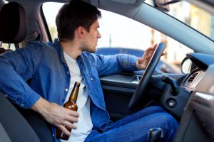 man driving with a beer bottle in his hand