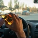 man drinking a beer behind the wheel