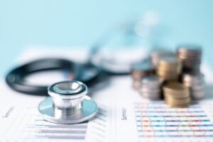 A stethoscope and some cash lie on top of medical bills. You may have to pay your medical bills from a personal injury settlement.
