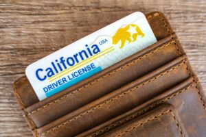 A California driver’s license in a brown letter wallet sits on a wood table after the driver lost two points for a DUI.