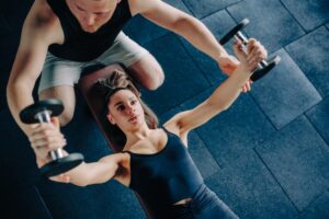 A personal trainer supervises a client while she works out.