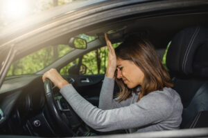 Frustrated woman driving a car wonders, “Does driving without insurance go on your record?”