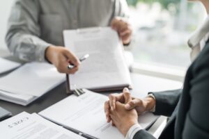 A person going over contracts during an attorney consultation after looking up how to choose the best DUI lawyer.
