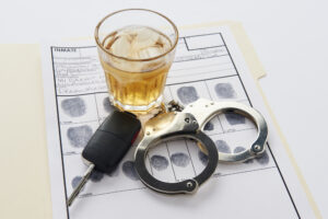 Handcuffs, whiskey, and keys on top of fingerprints. Charges for a DUI with hit and run in CA.
