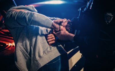 A man is getting arrested by a cop near cars. Here are 7 mistakes to avoid after a felony DUI arrest.