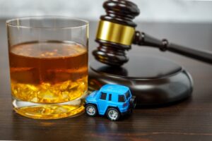 A toy car rests on a desk near an alcoholic drink and a gavel. Here are 7 mistakes to avoid if you’ve been charged with a second DUI.