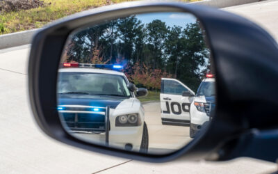Two police vehicles stop a sedan on a routine traffic stop while the driver wonders what things to do after a felony DUI arrest