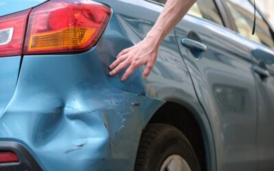 Driver's hand examining a dented car. 5 things to know about a hit and run DUI case.