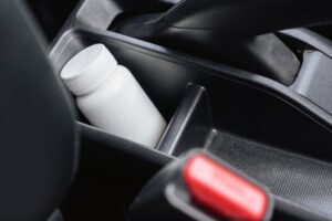 Close-up of a medicine bottle inside a car, using medication before driving concept. 5 mistakes to avoid in a prescription drug DUI case