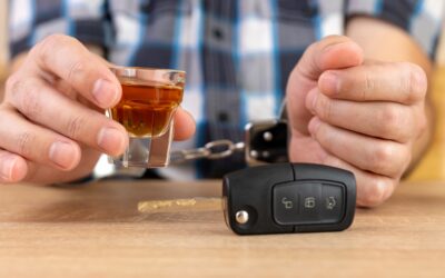 Hands hold a glass of alcohol and car keys. The person will later wonder about ways a lawyer can help with a DUI with injury case