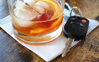 Drink and Drive, drunk driver concept - mixed drink liquor cocktail with key for vehicle at bar.