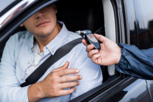 Driver taking breathalyzer from policeman while sitting in car. 6 mistakes to avoid when challenging breath test accuracy.