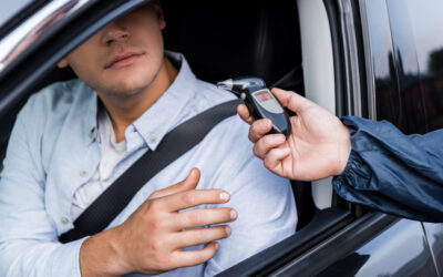 Driver taking breathalyzer from policeman while sitting in car. 6 mistakes to avoid when challenging breath test accuracy.