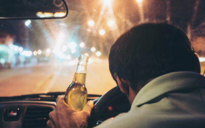 Drunk young man drives a car with a bottle of beer. Mistakes to avoid after an out-of-state DUI in California