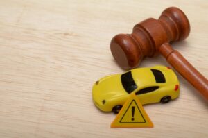 A gavel lying on a table next to a toy car and a mini caution sign to symbolize the question of how a DUI lawyer can help if you were wrongfully cited.