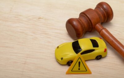 A gavel lying on a table next to a toy car and a mini caution sign to symbolize the question of how a DUI lawyer can help if you were wrongfully cited.